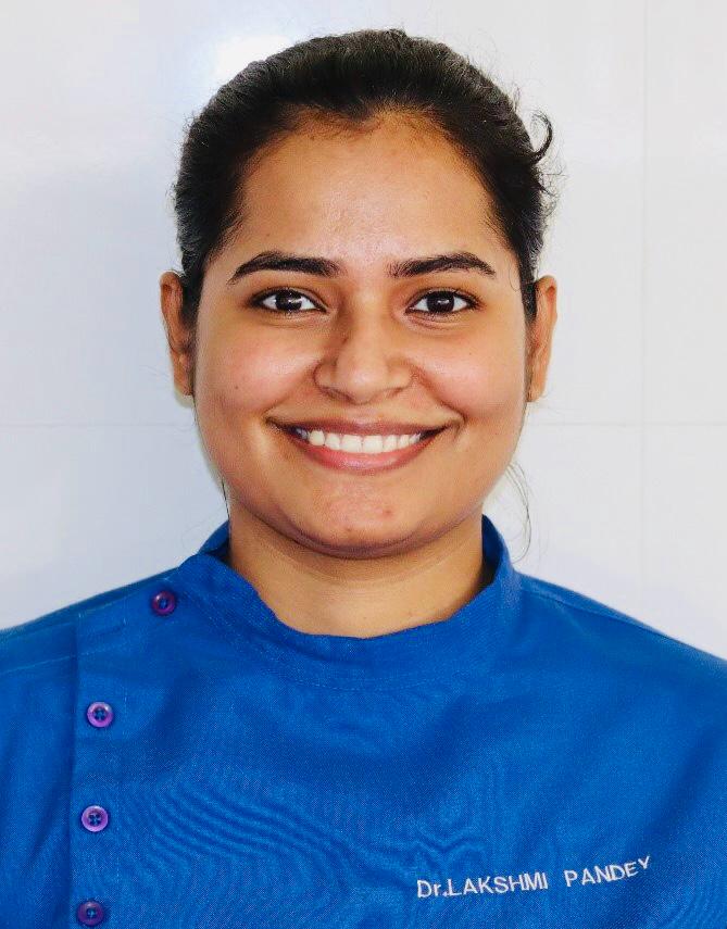 Dr. Lakshmi Pandey, MDS, PhD, the dentist at Root Care Multi-Speciality Dental Clinic in Nashik Road, Nashik, wearing blue clinical scrubs embroidered with her name.